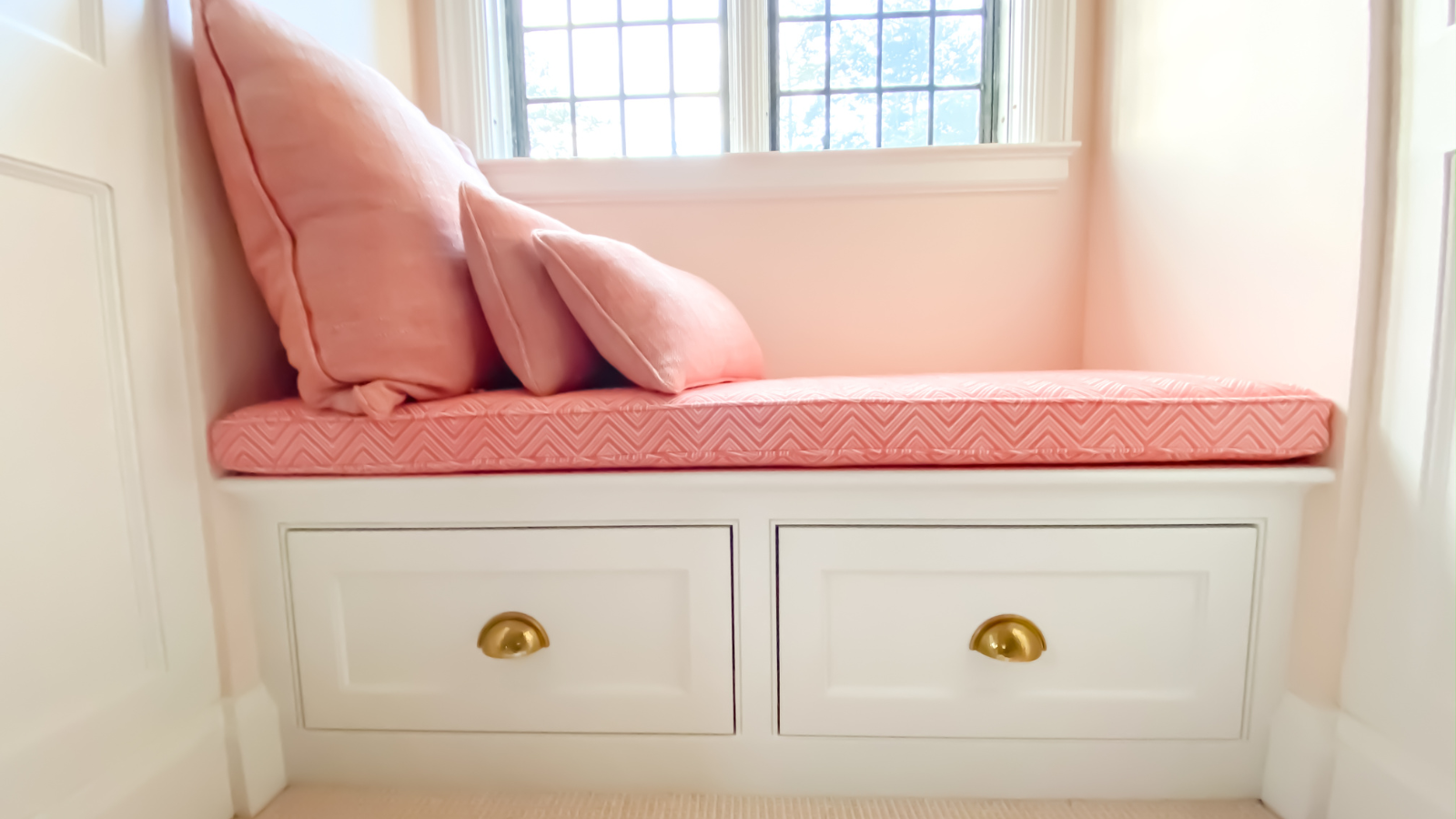 window seat with pink cushions and two drawers 